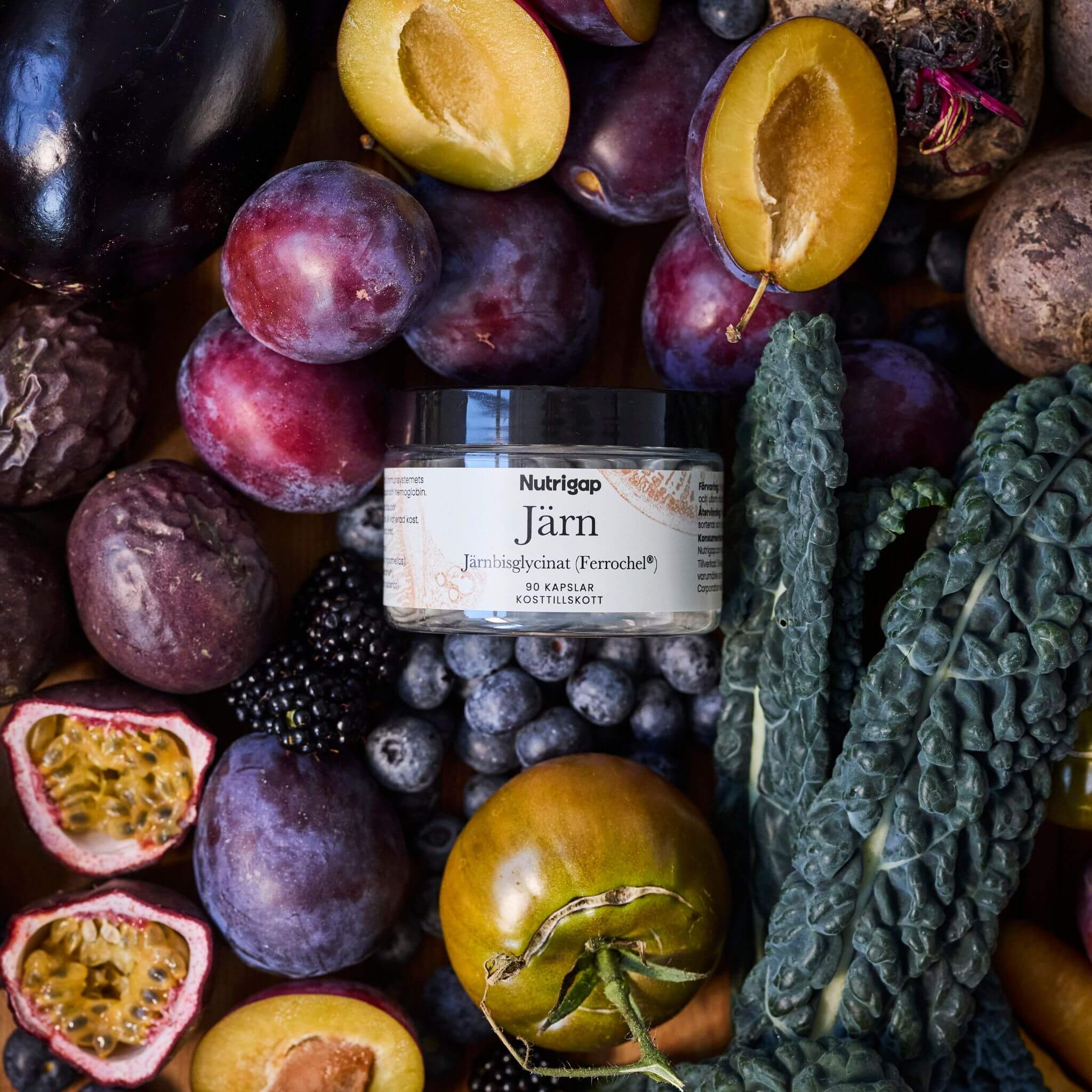 Burk med järntillskott omgiven av frukt, bär och grönsaker